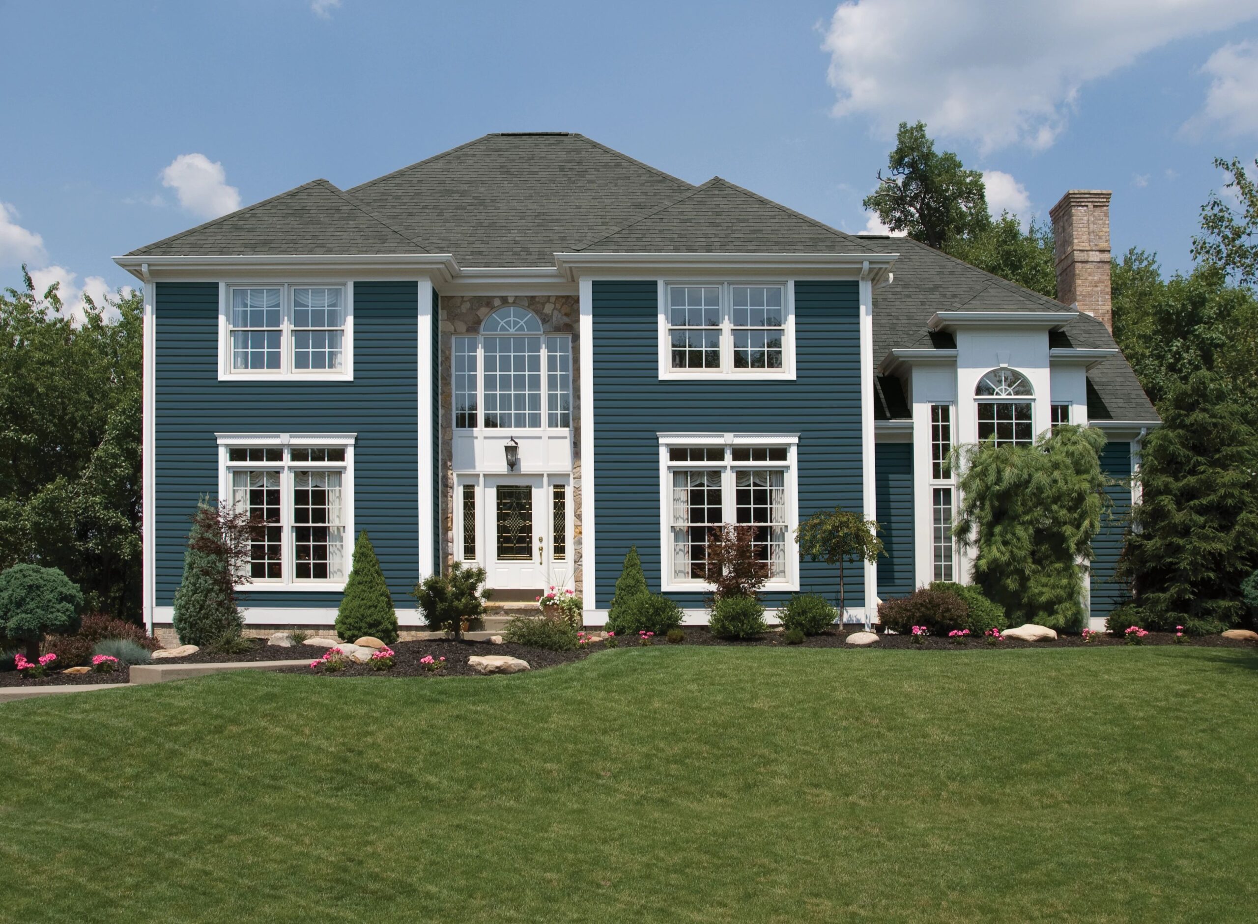 Blue-sided home with white trim and landscaped front garden